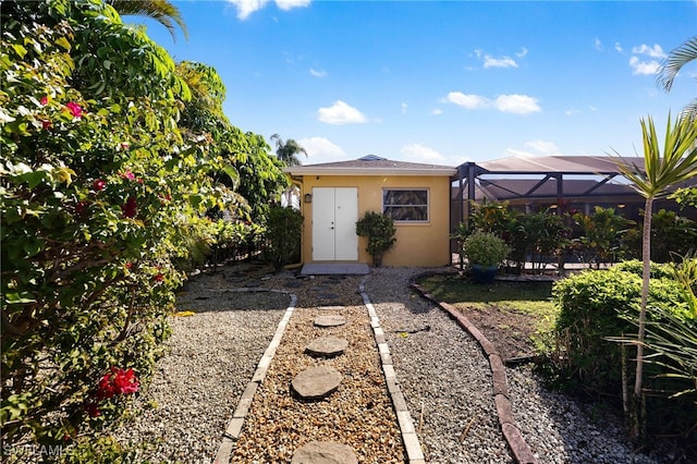 exterior space with an outbuilding, glass enclosure, and stucco siding