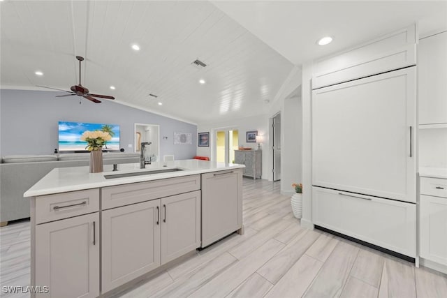 kitchen with paneled dishwasher, open floor plan, light countertops, and a sink