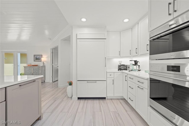 kitchen with light countertops, stainless steel double oven, paneled built in fridge, and white cabinetry