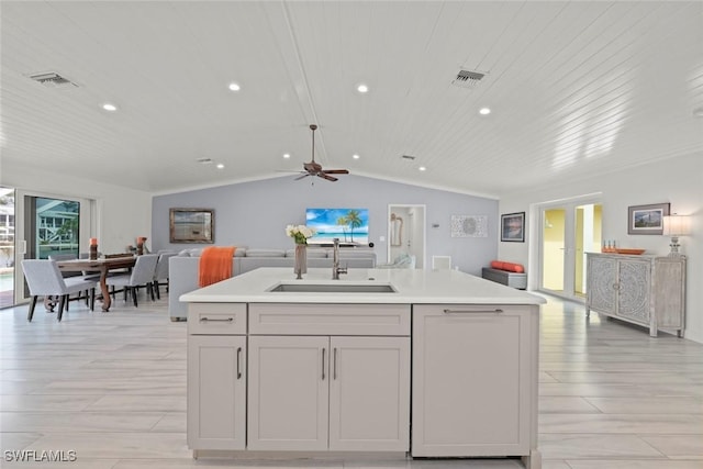 kitchen featuring visible vents, open floor plan, a sink, and light countertops