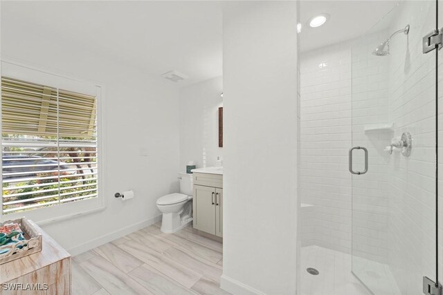 bathroom with toilet, a stall shower, vanity, and baseboards