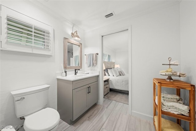 ensuite bathroom with visible vents, toilet, ornamental molding, connected bathroom, and vanity