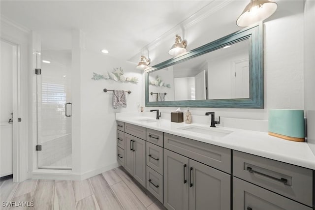 full bathroom featuring a sink, a shower stall, baseboards, and double vanity