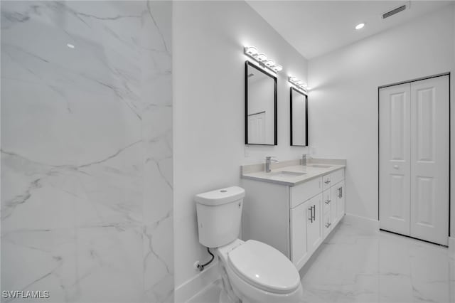 full bathroom with double vanity, marble finish floor, toilet, and a sink