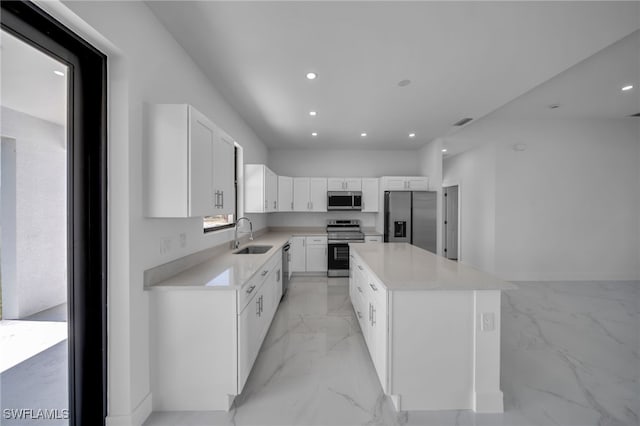 kitchen featuring a center island, marble finish floor, stainless steel appliances, white cabinets, and a sink