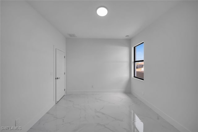 unfurnished room with marble finish floor, visible vents, and baseboards