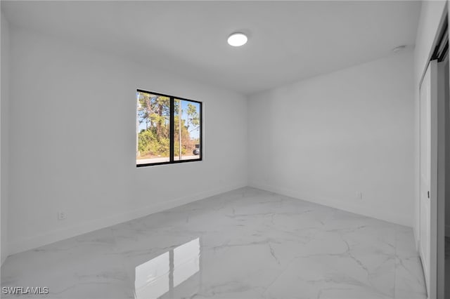 unfurnished room featuring marble finish floor and baseboards