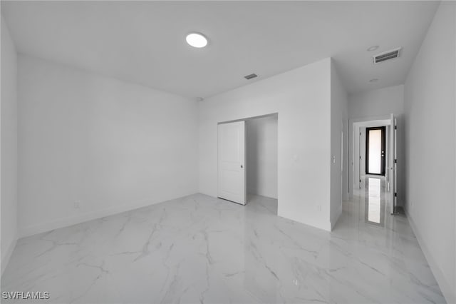 unfurnished bedroom with marble finish floor, a closet, and visible vents