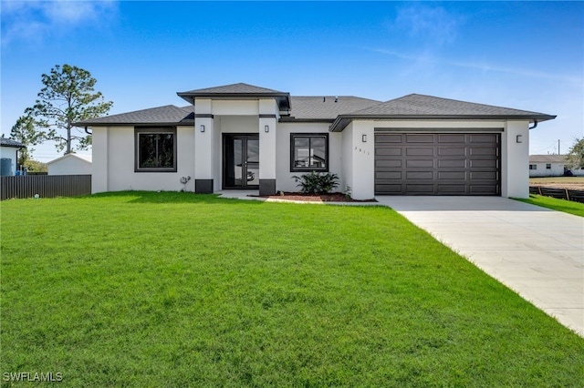 prairie-style home with a garage, concrete driveway, fence, a front lawn, and stucco siding