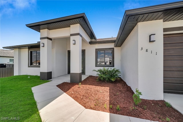 view of exterior entry featuring a yard and stucco siding