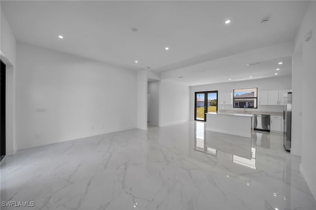 unfurnished living room with marble finish floor, a sink, and recessed lighting