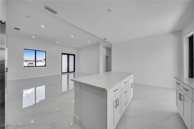 kitchen featuring a center island, marble finish floor, visible vents, and white cabinetry