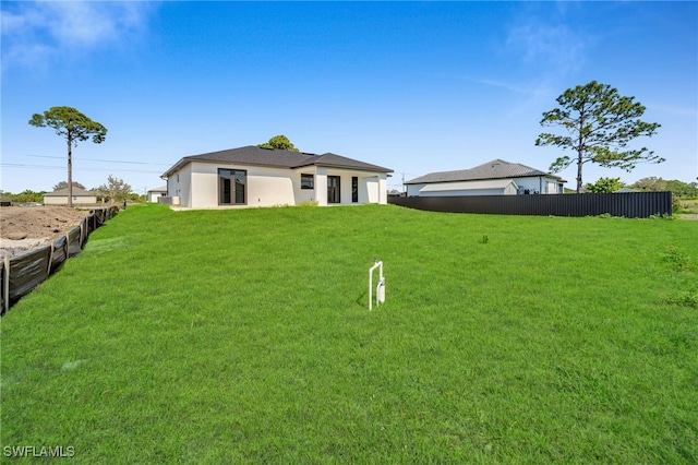 rear view of property with fence and a lawn