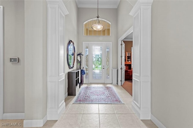 foyer featuring light tile patterned floors, ornamental molding, baseboards, and ornate columns