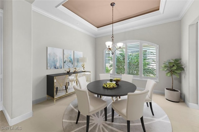 dining space featuring a raised ceiling, crown molding, baseboards, and an inviting chandelier