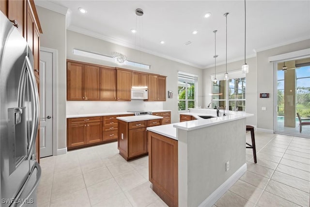 kitchen featuring an island with sink, white microwave, brown cabinets, stainless steel refrigerator with ice dispenser, and a sink