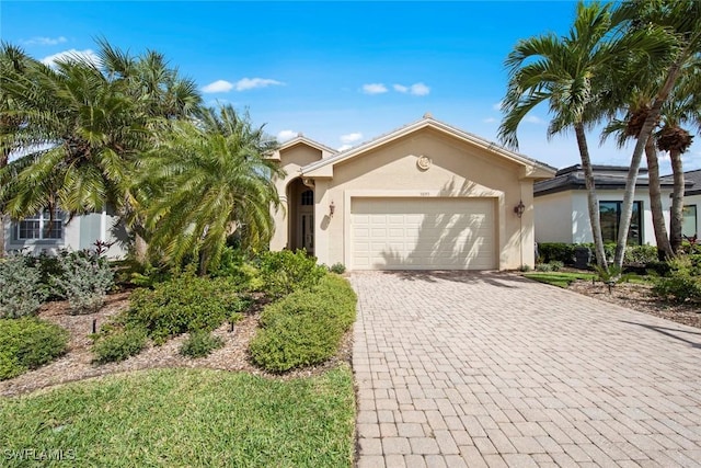 view of front of house with decorative driveway, an attached garage, and stucco siding