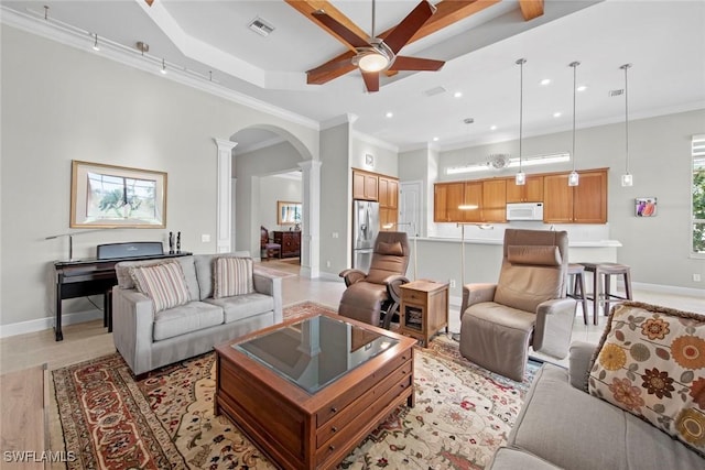 living room featuring arched walkways, visible vents, baseboards, ornamental molding, and ornate columns