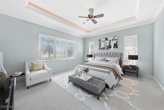 carpeted bedroom with baseboards, a tray ceiling, ceiling fan, and crown molding