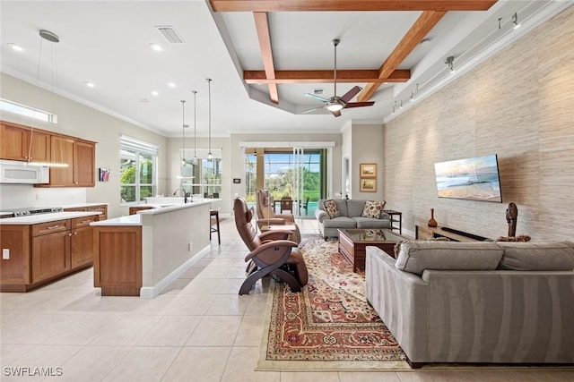 living room with a wealth of natural light, visible vents, beamed ceiling, and light tile patterned flooring