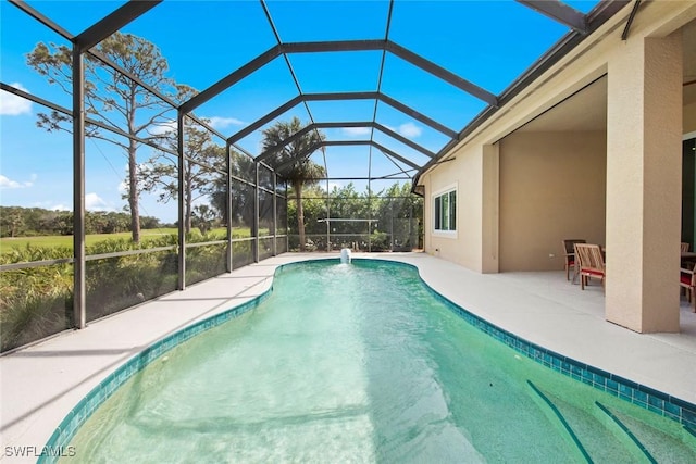 outdoor pool featuring glass enclosure and a patio