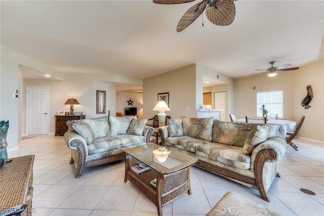 living area with light tile patterned floors, ceiling fan, and baseboards