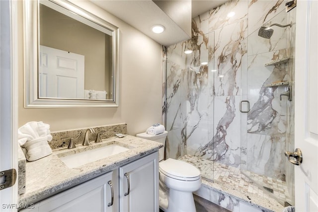 full bath with toilet, a marble finish shower, and vanity