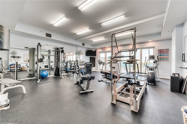 workout area with a textured ceiling, visible vents, and baseboards