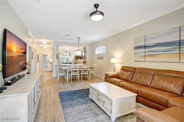 living area featuring light wood-style floors, ornamental molding, and baseboards