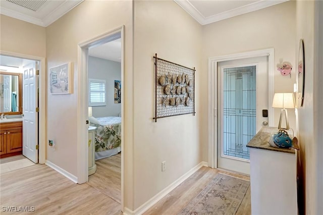 interior space with baseboards, visible vents, light wood-style flooring, crown molding, and a sink