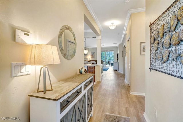 hallway with light wood-style floors, baseboards, and ornamental molding