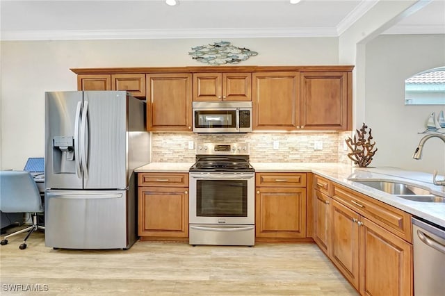 kitchen with light wood-style floors, stainless steel appliances, a sink, and brown cabinetry