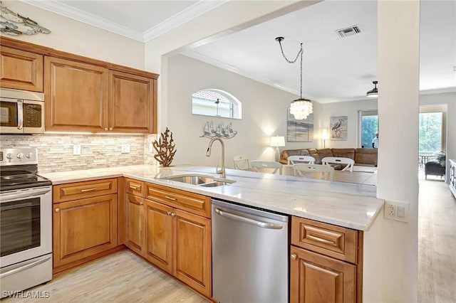 kitchen with light stone counters, decorative backsplash, appliances with stainless steel finishes, ornamental molding, and a sink