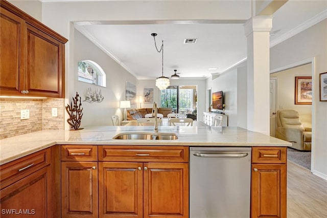 kitchen with decorative columns, stainless steel dishwasher, ornamental molding, open floor plan, and a sink