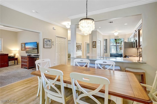 dining room with ornamental molding, light wood-type flooring, visible vents, and baseboards