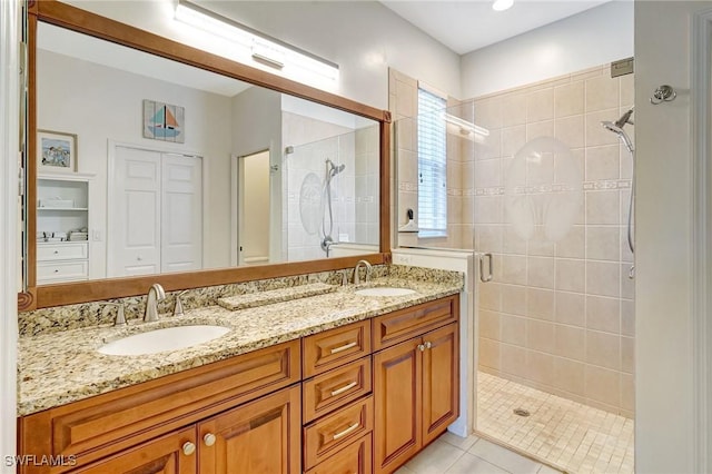 bathroom with double vanity, a stall shower, tile patterned flooring, and a sink