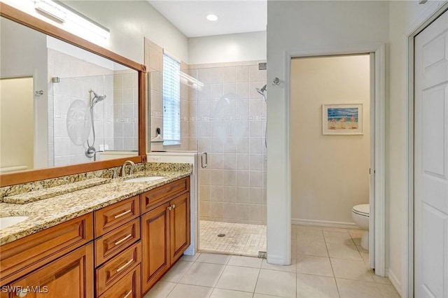 bathroom featuring double vanity, toilet, a stall shower, a sink, and tile patterned flooring