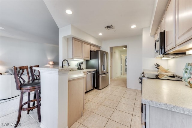 kitchen with stainless steel appliances, light countertops, visible vents, a peninsula, and a kitchen bar