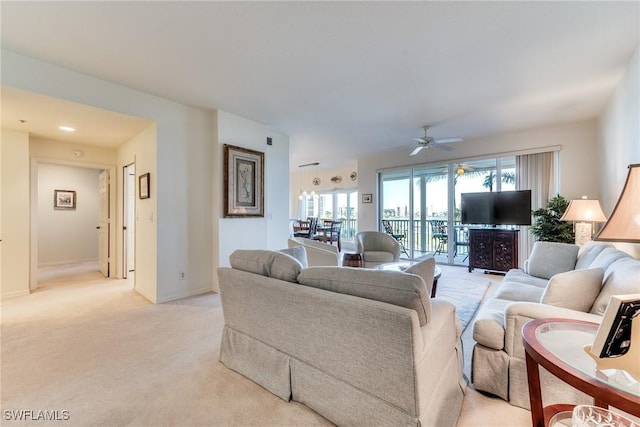 living area featuring a ceiling fan, light colored carpet, and baseboards