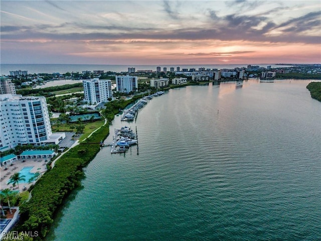 aerial view at dusk featuring a water view and a city view