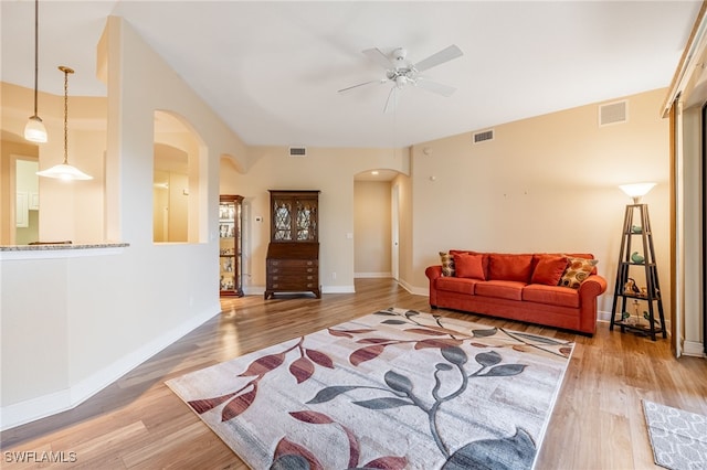 living area with arched walkways, visible vents, baseboards, and wood finished floors