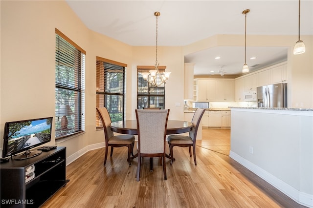 dining space featuring light wood finished floors, recessed lighting, baseboards, and an inviting chandelier