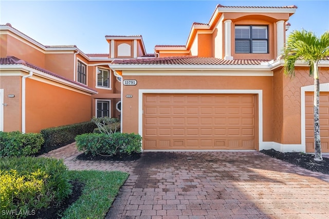 view of front of home with a garage, a tile roof, and stucco siding