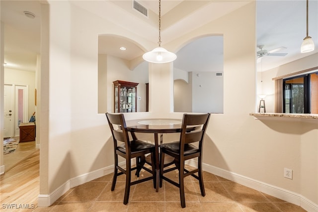 tiled dining area with arched walkways, ceiling fan, visible vents, and baseboards