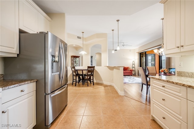 kitchen featuring arched walkways, light tile patterned flooring, white cabinetry, open floor plan, and stainless steel fridge