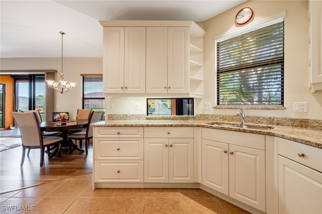 kitchen featuring decorative light fixtures, a notable chandelier, open shelves, a sink, and light stone countertops