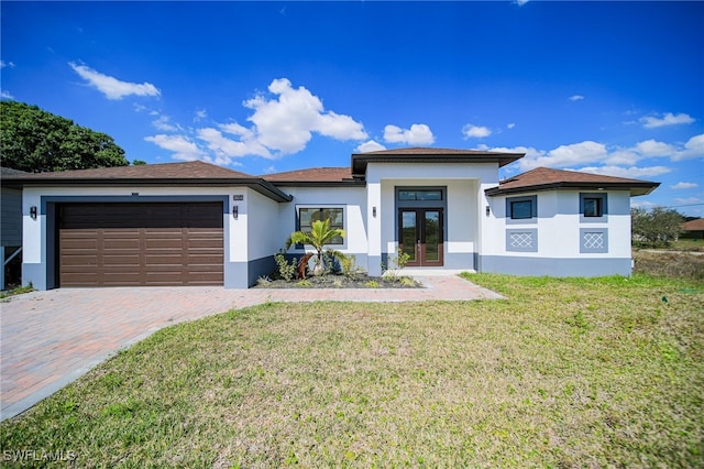 prairie-style home featuring decorative driveway, french doors, stucco siding, an attached garage, and a front lawn