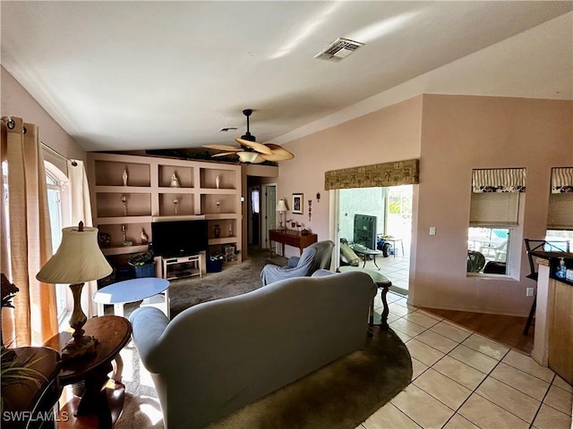 living area with lofted ceiling, a healthy amount of sunlight, visible vents, and light tile patterned flooring