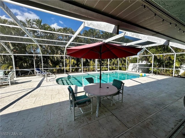 outdoor pool featuring glass enclosure and a patio area