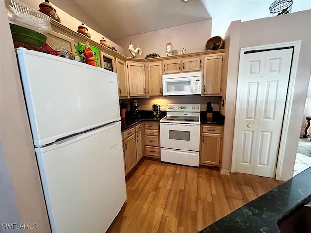 kitchen featuring white appliances, dark countertops, vaulted ceiling, light wood-style floors, and light brown cabinets